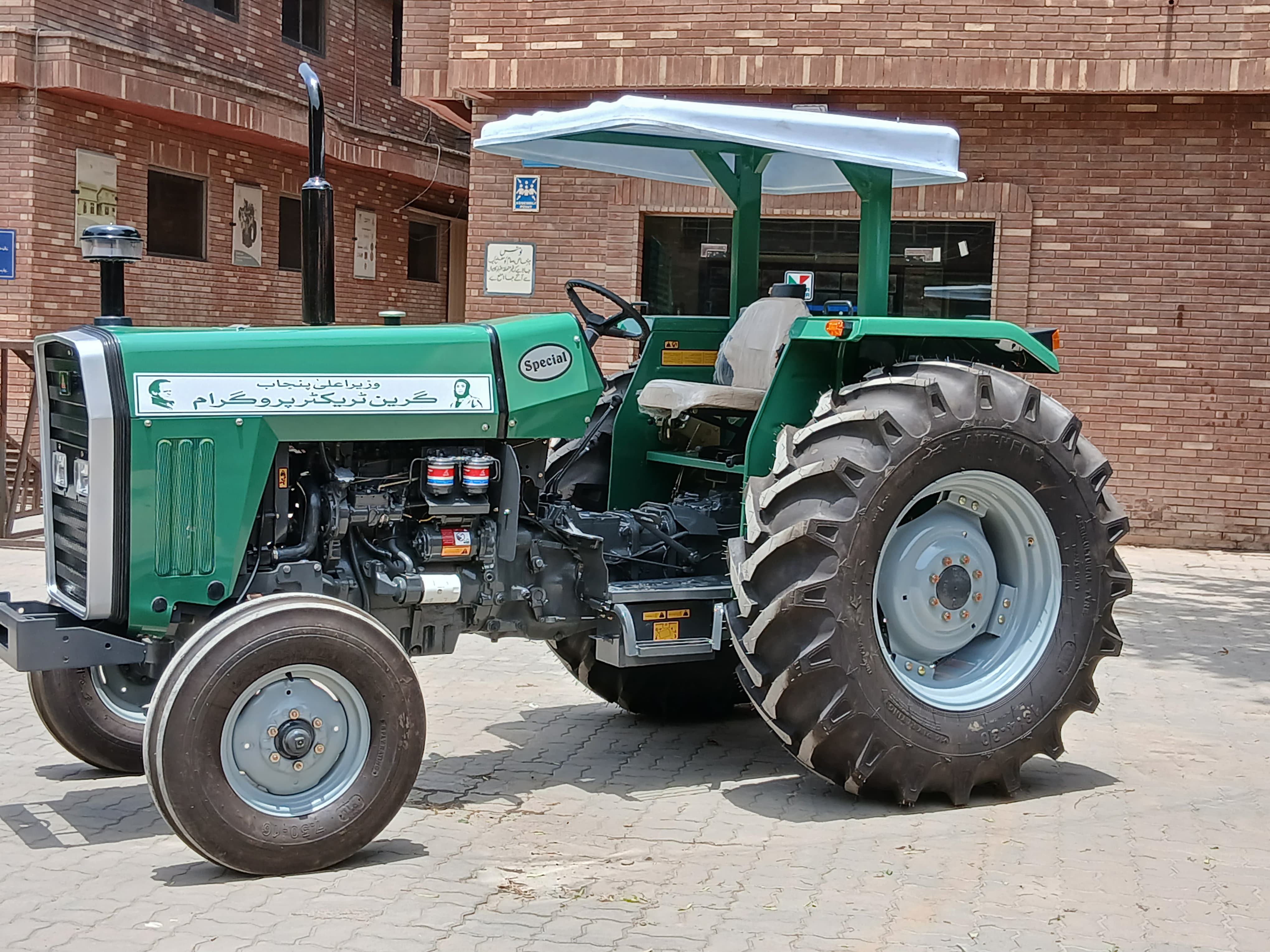 ATS Tractor 290 Special Edition - Green model with Urdu branding and white protective canopy in industrial courtyard